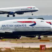 A British Airways plane lands as two other grounded planes sit on the runway at Heathrow Airport.