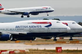 A British Airways plane lands as two other grounded planes sit on the runway at Heathrow Airport.