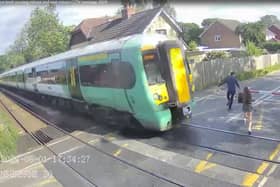 Shocking CCTV films the moment a girl risks her life at a level crossing, walking just a couples of metres in front of an advancing train.