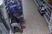 Video grab of Nicolae Boia crouched behind a trolley and filling his bag with unpaid for goods.