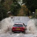 Car drives along flooded road.