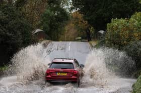 Car drives along flooded road.