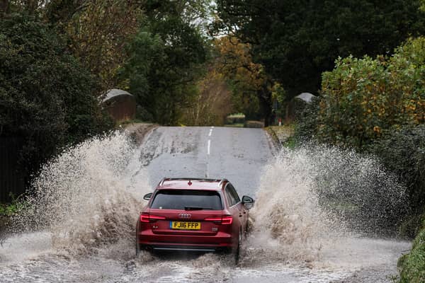Car drives along flooded road.
