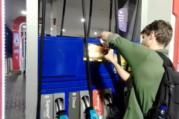 Dr Patrick Hart cracks the display panels of petrol pumps at Esso Thurrock Services on the M25 on August 24 2022. 