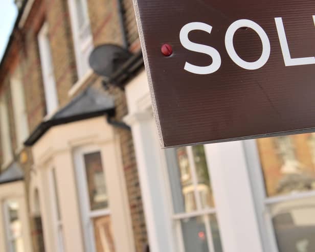 An estate agent's "sold" board stands outside a residential building.