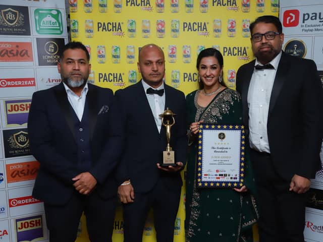 Juber Ahmed (holding the trophy) picks up his award with colleagues and family