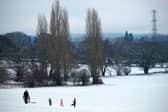 Family play on snow covered hill.